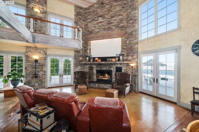 living room with french doors, a stone fireplace, a high ceiling, and wood-type flooring