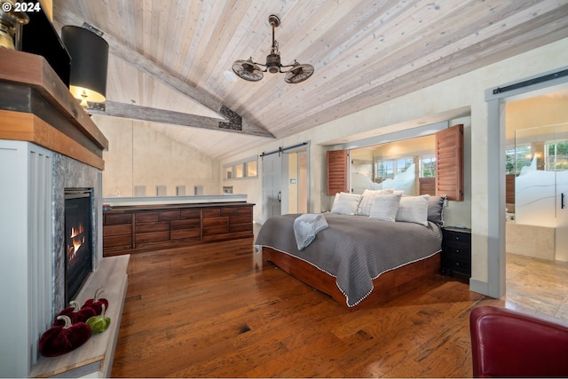 bedroom featuring lofted ceiling, multiple windows, a fireplace, and a barn door