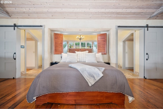 bedroom with wood ceiling, light hardwood / wood-style flooring, and a barn door