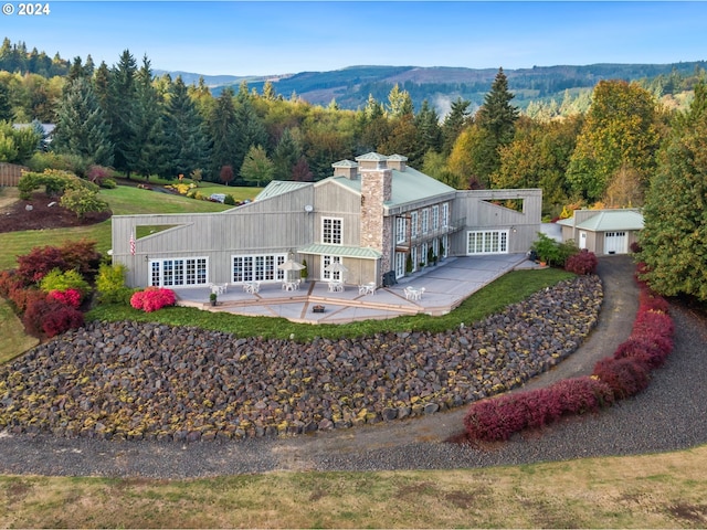 rear view of property with a patio, a mountain view, and a swimming pool