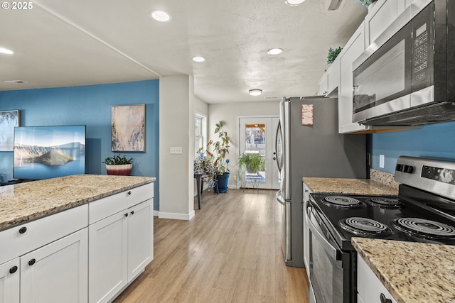 kitchen featuring light hardwood / wood-style floors, white cabinets, light stone counters, and appliances with stainless steel finishes