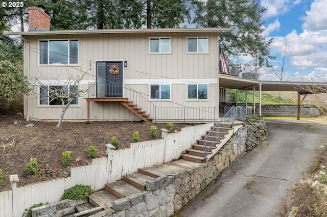 split foyer home with an attached carport, driveway, stairs, and a chimney