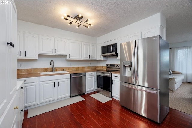 kitchen featuring white cabinets, a sink, stainless steel appliances, and dark wood-type flooring