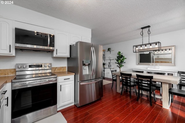 kitchen with hanging light fixtures, dark wood-type flooring, stainless steel appliances, a textured ceiling, and white cabinets