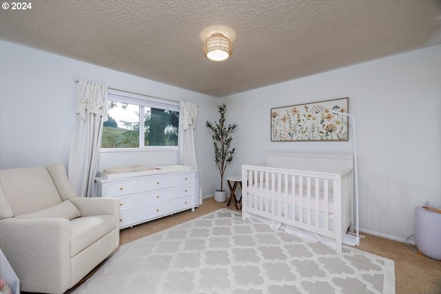 bedroom featuring a textured ceiling, light colored carpet, and a nursery area