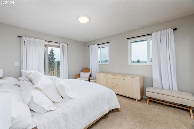 bedroom with light colored carpet and a textured ceiling