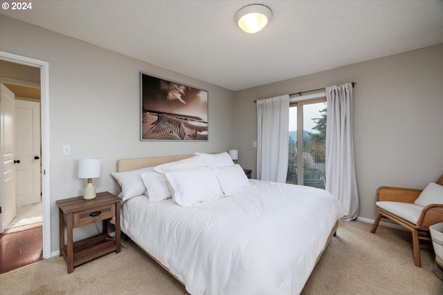 bedroom with light colored carpet, baseboards, and a textured ceiling