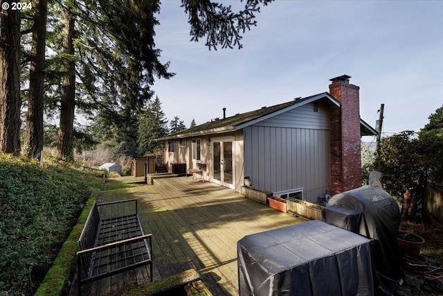 back of property with board and batten siding, a chimney, a deck, and french doors