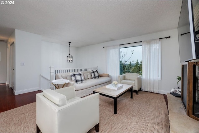 living room featuring baseboards, an inviting chandelier, wood finished floors, and a textured ceiling