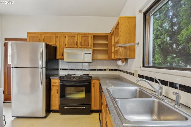 kitchen with brown cabinets, black electric range, a sink, freestanding refrigerator, and white microwave