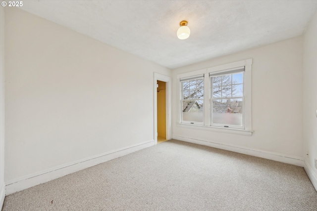 empty room with baseboards and carpet