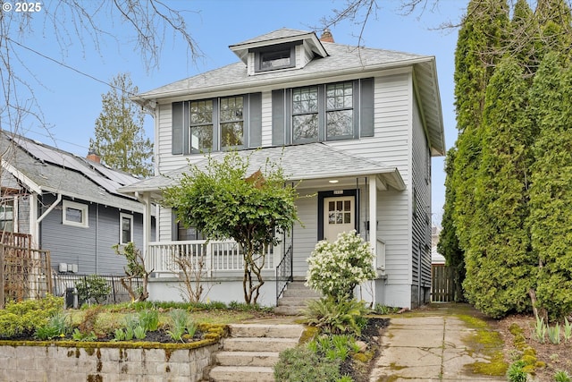 traditional style home featuring roof with shingles, covered porch, and fence