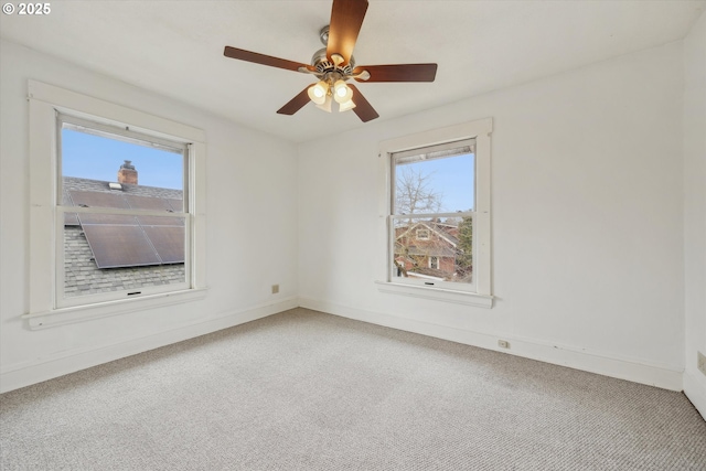 carpeted empty room featuring baseboards and ceiling fan