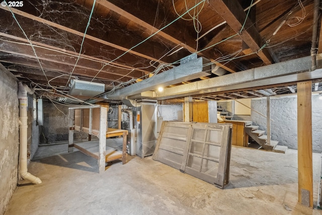 unfinished basement featuring heating unit and stairs