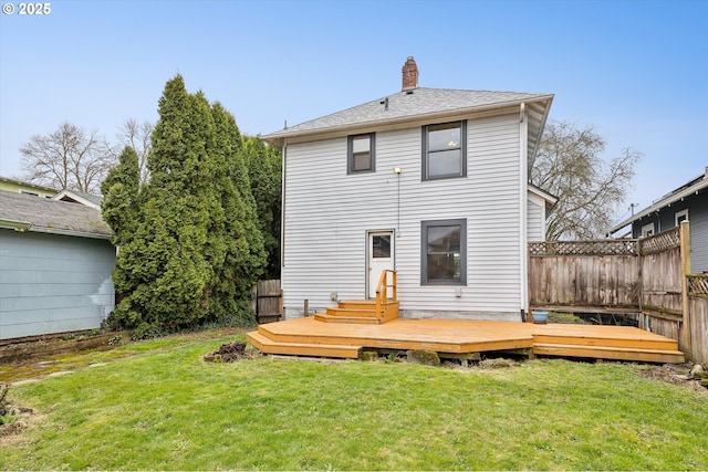 rear view of property with a wooden deck, fence, a lawn, and a chimney