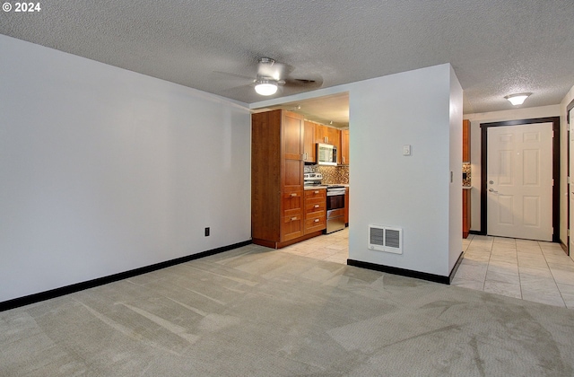 carpeted empty room featuring ceiling fan and a textured ceiling