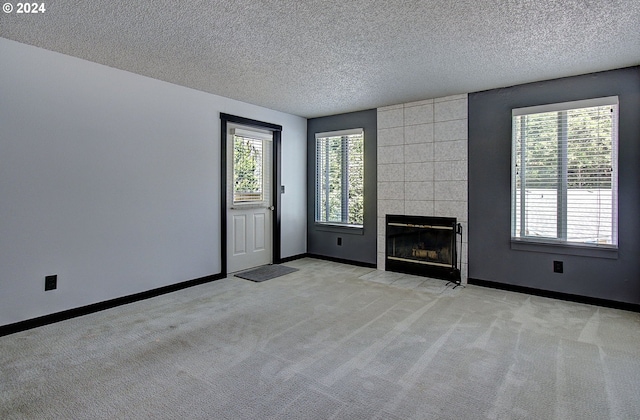 unfurnished living room with tile walls, light carpet, a textured ceiling, and a fireplace