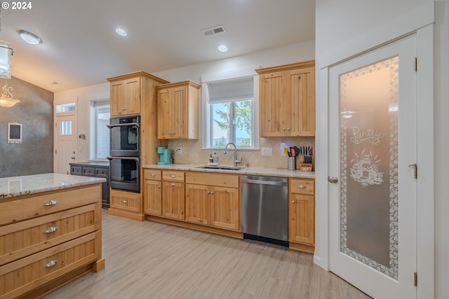 kitchen with light stone counters, backsplash, black appliances, a center island, and light wood-type flooring