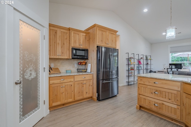 kitchen with hanging light fixtures, light stone counters, black appliances, lofted ceiling, and a center island