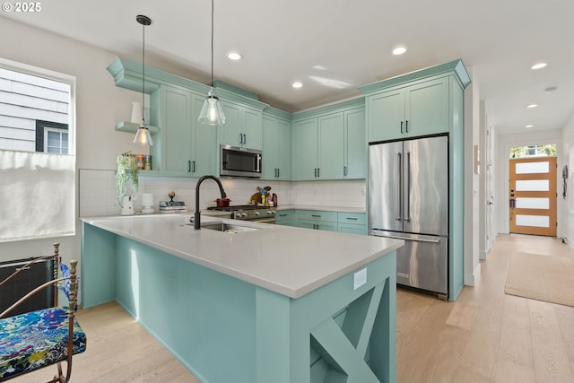 6332 NE 30th Ave, Portland, OR 97211 - kitchen with appliances with stainless steel finishes, a sink, a peninsula, light wood-style flooring, and tasteful backsplash