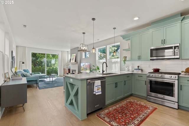 6332 NE 30th Ave, Portland, OR 97211 - kitchen with stainless steel appliances, green cabinetry, a sink, open shelves, and light wood-type flooring