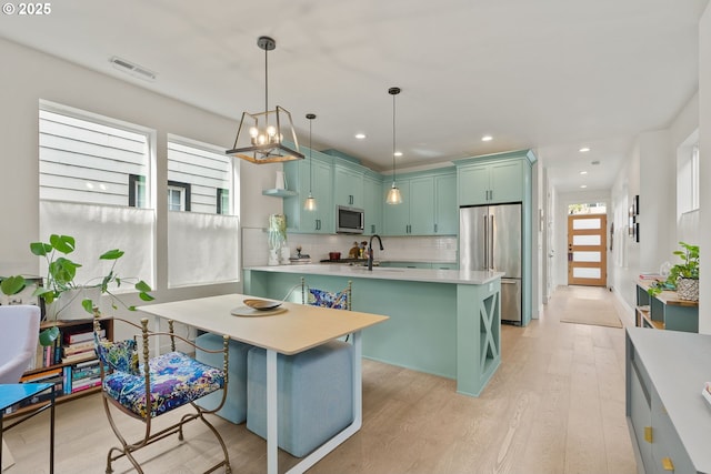 6332 NE 30th Ave, Portland, OR 97211 - kitchen with stainless steel appliances, light countertops, light wood-style floors, a sink, and tasteful backsplash