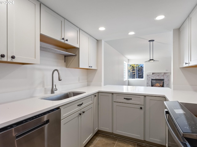 kitchen featuring sink, white cabinets, kitchen peninsula, a fireplace, and stainless steel appliances