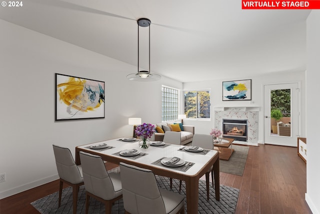 dining area with a high end fireplace and dark wood-type flooring