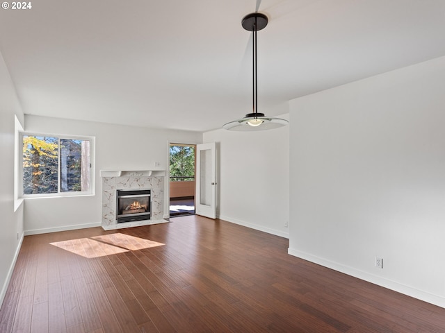 unfurnished living room with a high end fireplace and dark wood-type flooring