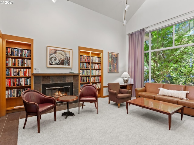 living area with carpet floors, built in features, high vaulted ceiling, and a tile fireplace