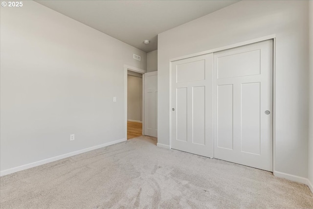 unfurnished bedroom featuring light carpet and a closet