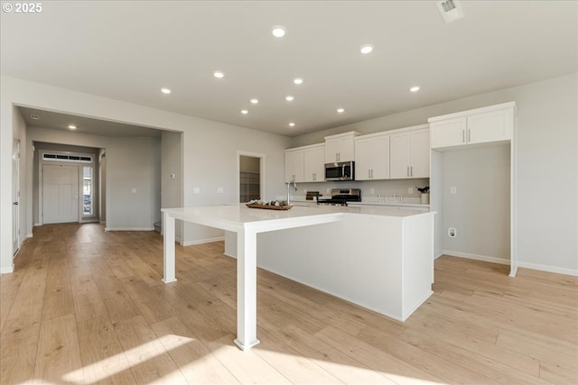 kitchen featuring a large island with sink, white cabinetry, and appliances with stainless steel finishes