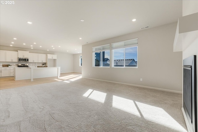 unfurnished living room featuring light colored carpet