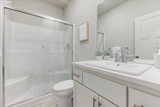 bathroom with tile patterned floors, toilet, a shower with door, and vanity