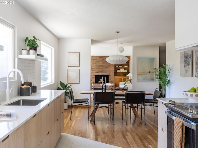 kitchen featuring sink, white cabinetry, hanging light fixtures, light hardwood / wood-style flooring, and decorative backsplash