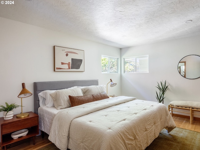 bedroom with a textured ceiling and wood-type flooring