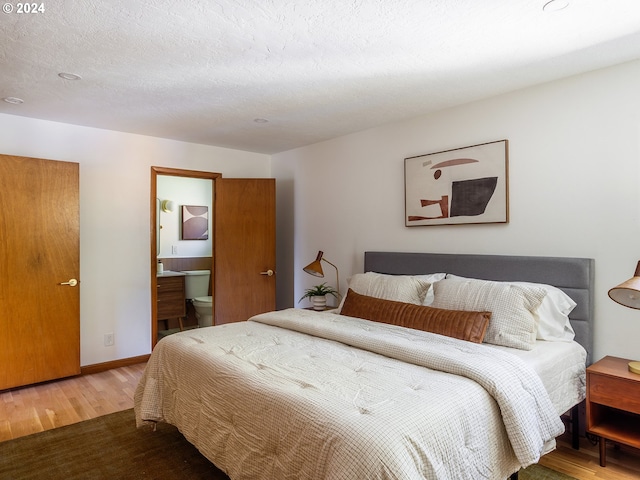 bedroom featuring a textured ceiling, hardwood / wood-style floors, and ensuite bathroom