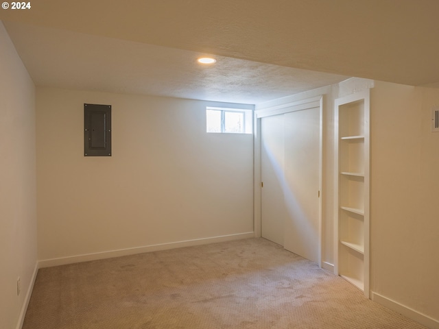 basement with a textured ceiling, electric panel, and light colored carpet