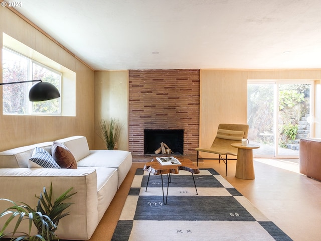 living room with ornamental molding, a large fireplace, and wood walls