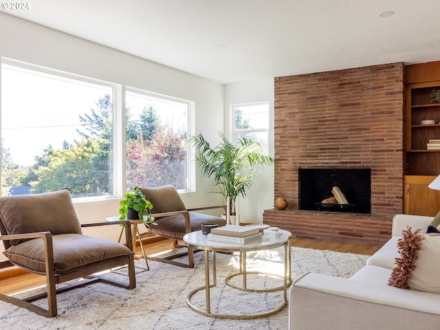 living room with a healthy amount of sunlight, hardwood / wood-style floors, and a brick fireplace