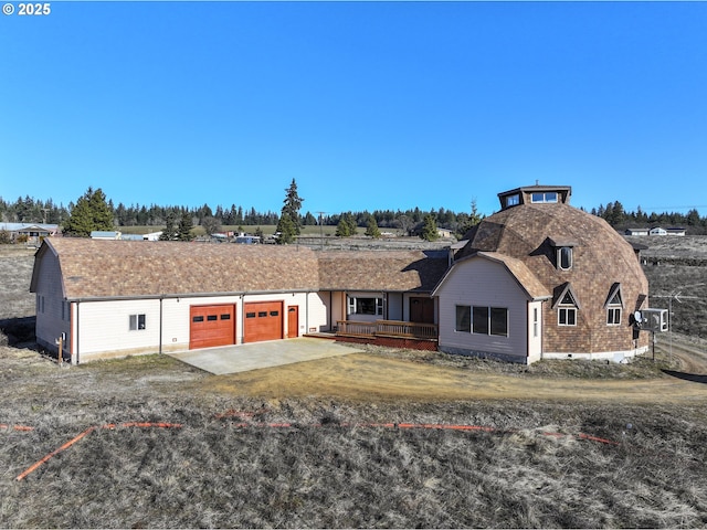 view of front of property with a gambrel roof, concrete driveway, a garage, and a shingled roof