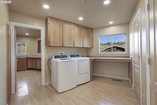 washroom with independent washer and dryer, cabinets, and light wood-type flooring