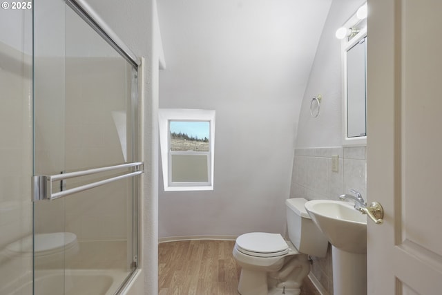 bathroom with enclosed tub / shower combo, wood-type flooring, toilet, and tile walls