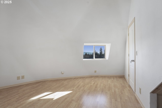 empty room featuring light wood-type flooring and a towering ceiling