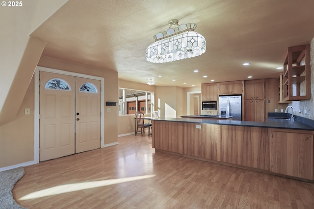 kitchen featuring sink, decorative light fixtures, stainless steel appliances, and light wood-type flooring