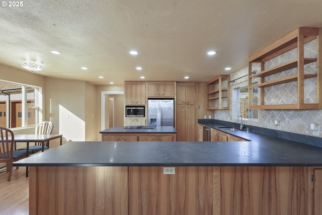 kitchen with stainless steel appliances, light hardwood / wood-style floors, sink, tasteful backsplash, and a textured ceiling