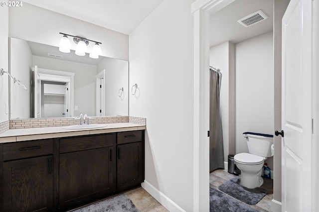 bathroom with vanity, toilet, and tasteful backsplash