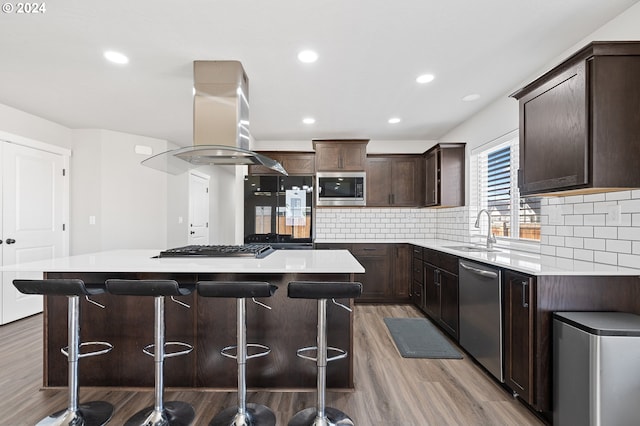 kitchen featuring hardwood / wood-style flooring, island range hood, a center island, and stainless steel appliances