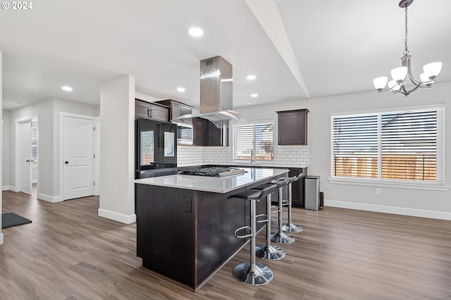 kitchen with tasteful backsplash, a kitchen island, island exhaust hood, dark hardwood / wood-style floors, and black refrigerator