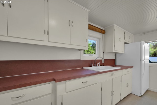 kitchen featuring sink, white refrigerator, and white cabinets